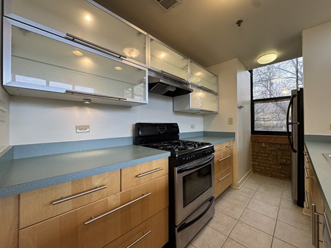 A kitchen with a black stove top oven and wooden cabinets.