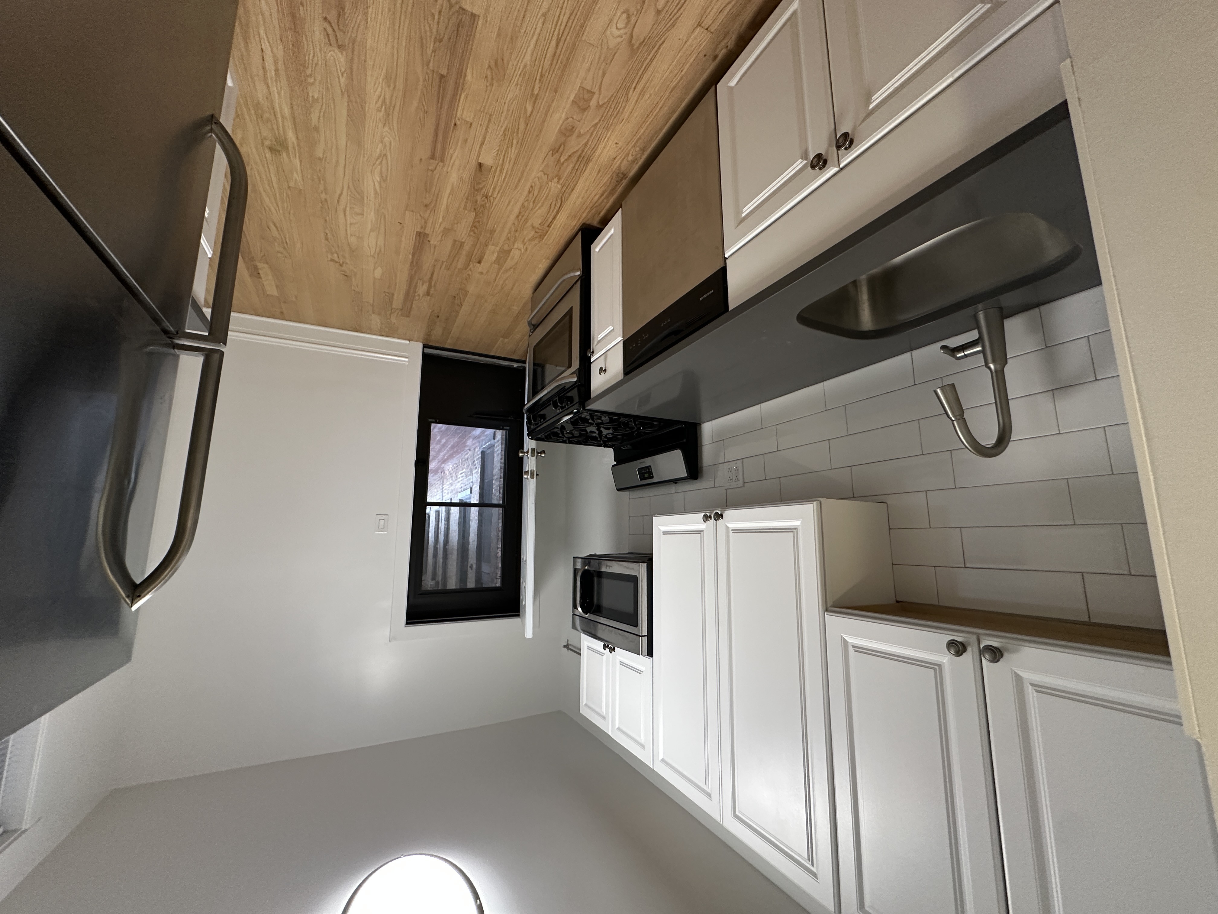 A modern kitchen with white cabinets and a wooden ceiling.