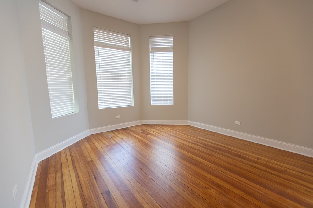 A room with wooden floors and two windows.