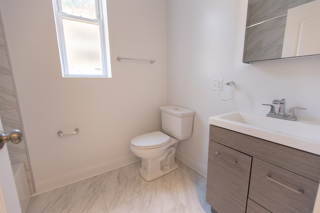 A white toilet in a small bathroom with a sink and mirror.
