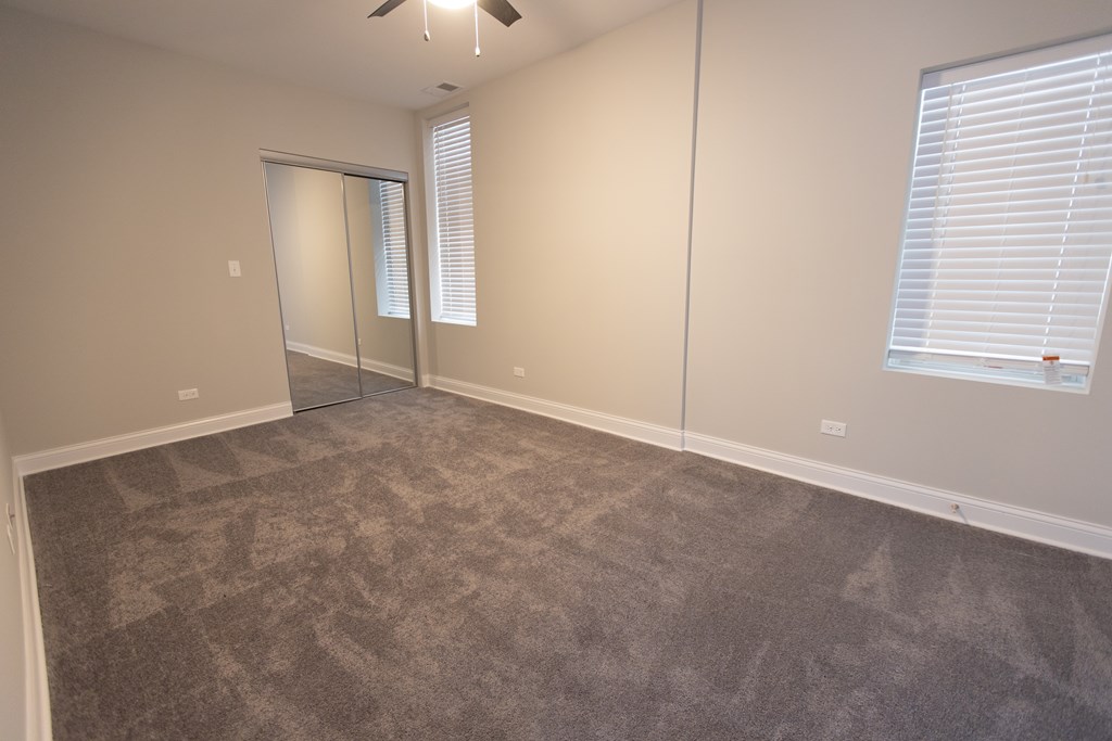 A room with a carpeted floor and a ceiling fan.