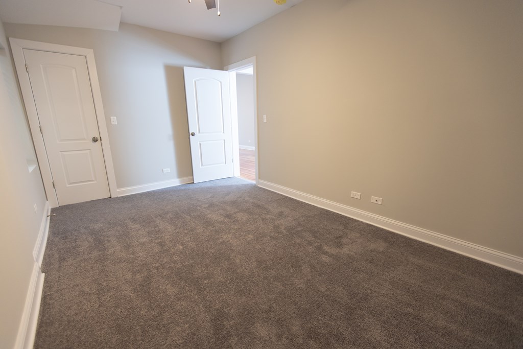 A room with carpeted floor and two doors.