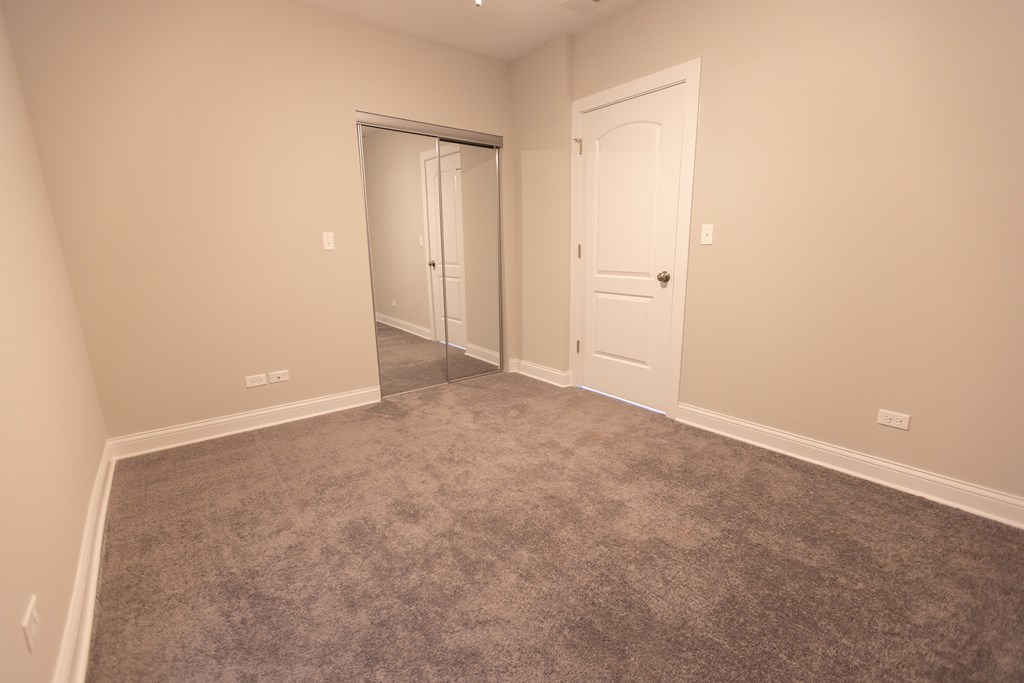 A room with a carpeted floor and two doors.