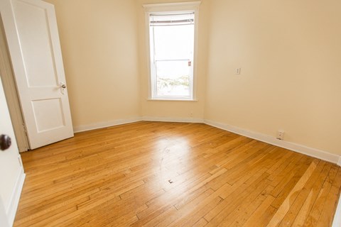 an empty room with wooden floors and a window