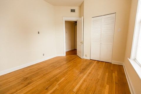 an empty living room with wood floors and a closet