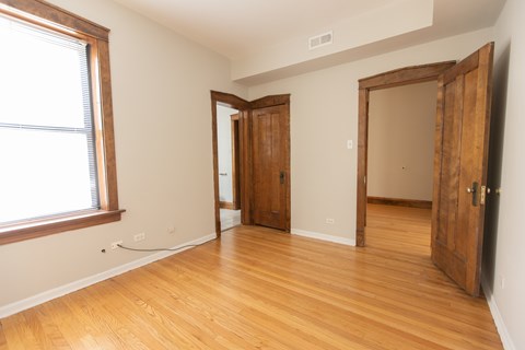A room with wooden floors and a window on the left side.