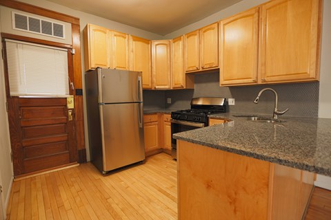 A kitchen with wooden cabinets and a granite counter.