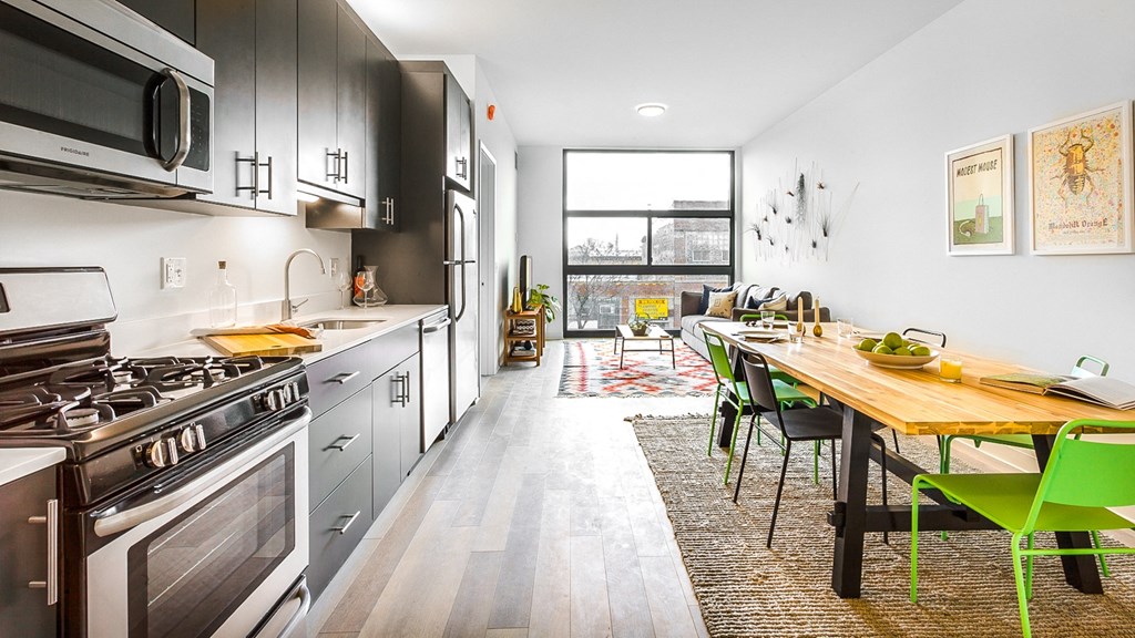 Modern and well-equipped kitchen at L Logan Square Apartments, featuring gray cabinets, sleek countertops, state-of-the-art appliances, and ample storage.