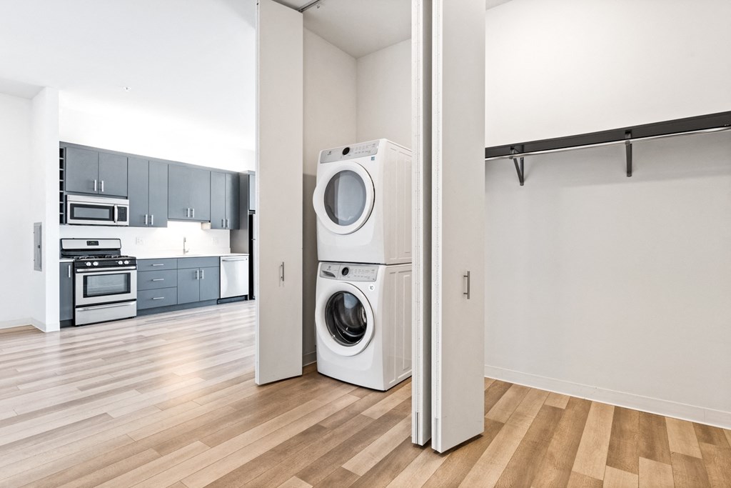 Hallway at L Logan Square Apartments with a view of the stylish kitchen in the background and convenient washer and dryer units, combining functionality and modern design
