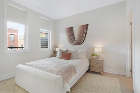 A bedroom with a large bed and a window with a view of a building outside.