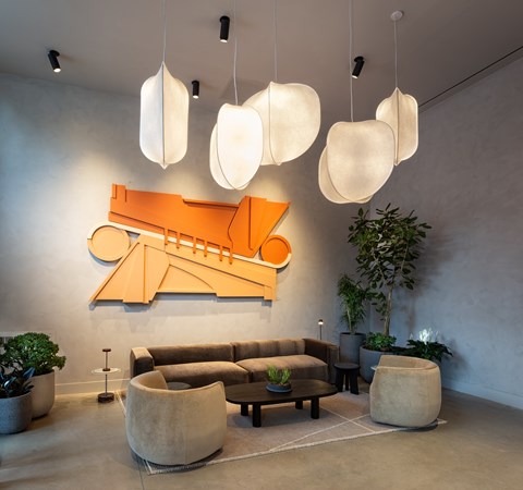 A modern living room with a large orange abstract art piece on the wall and a variety of seating options.