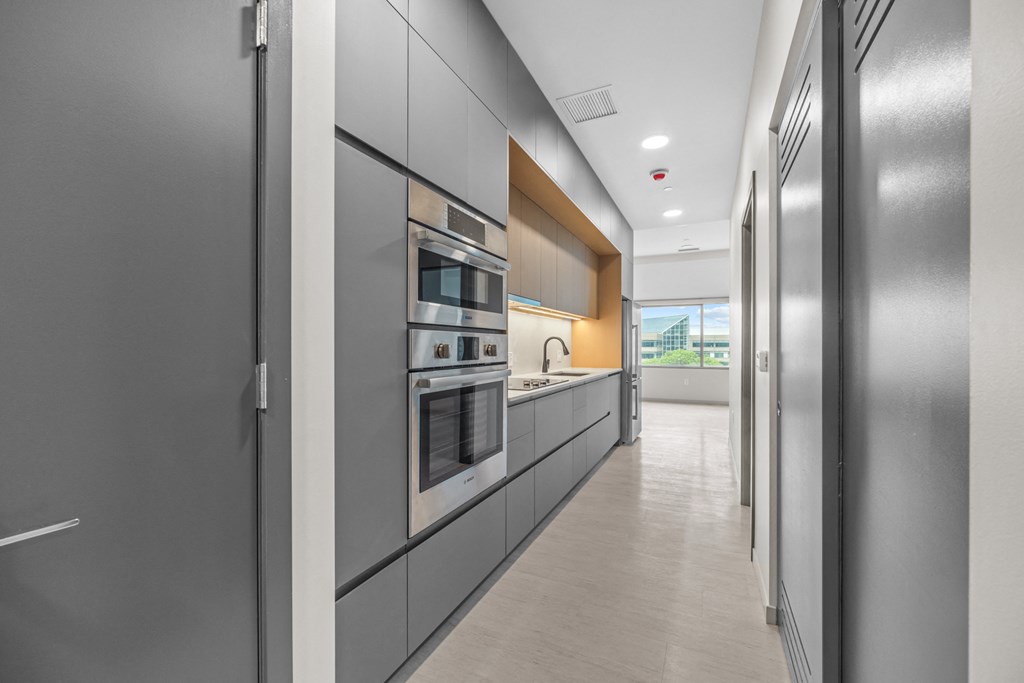 a long kitchen with gray cabinets and stainless steel appliances