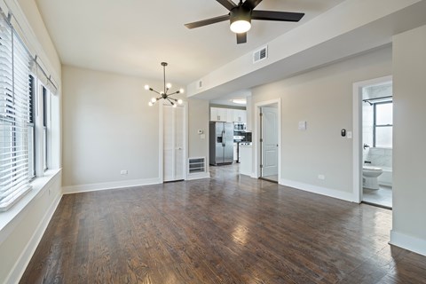 A spacious room with a ceiling fan and hardwood floors.