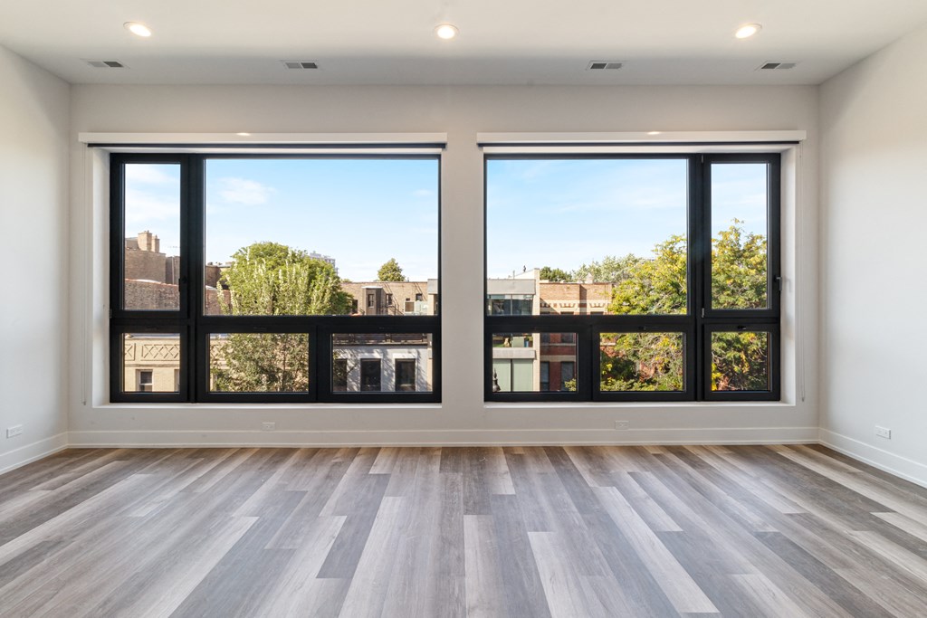 an empty living room with large windows and a view of the city