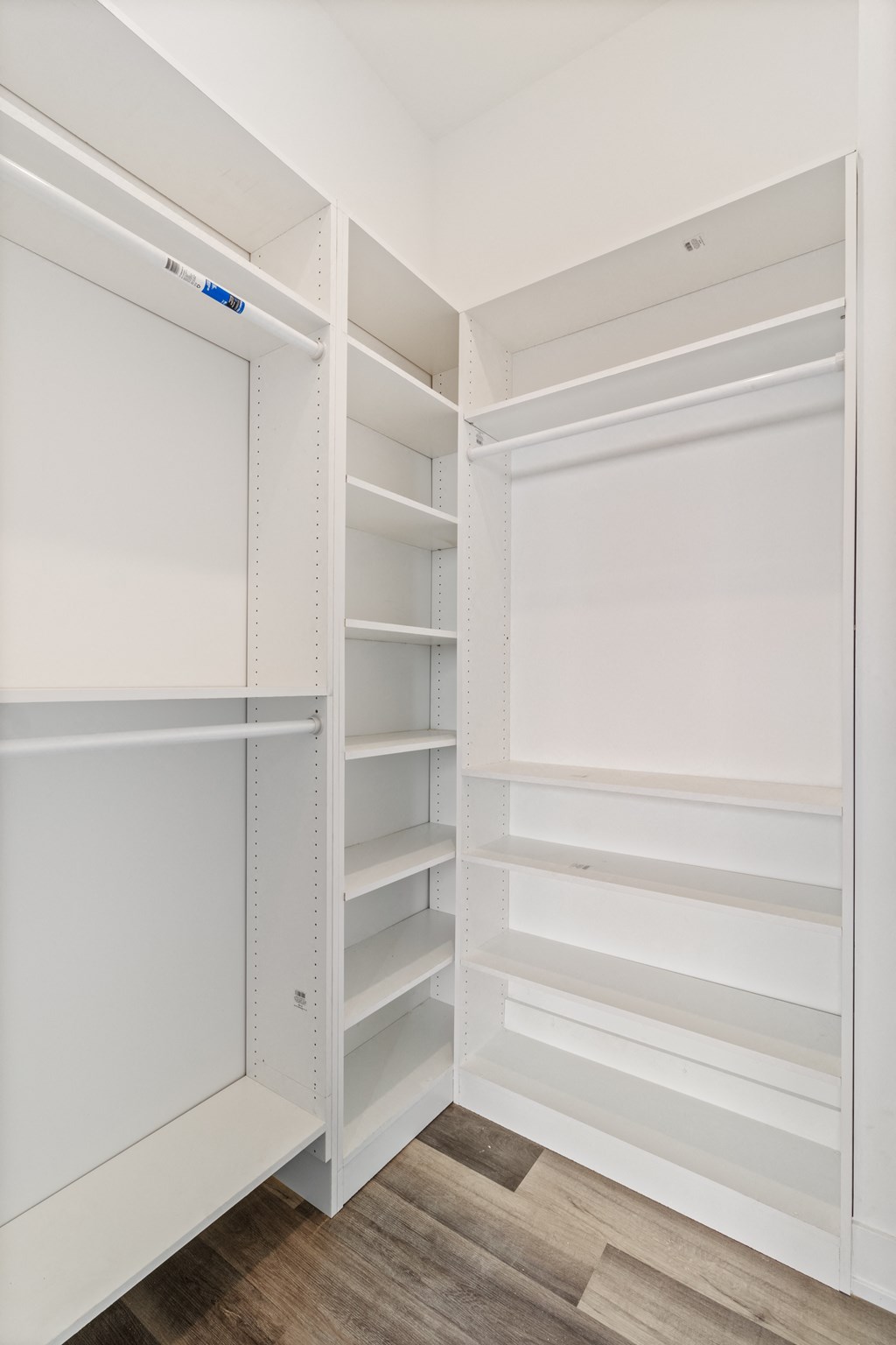 a walk in closet in a home with white shelving and