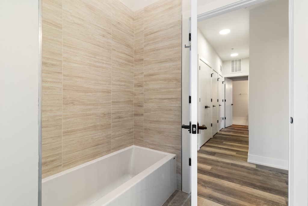 a bathroom with a bath tub and a hallway with stalls