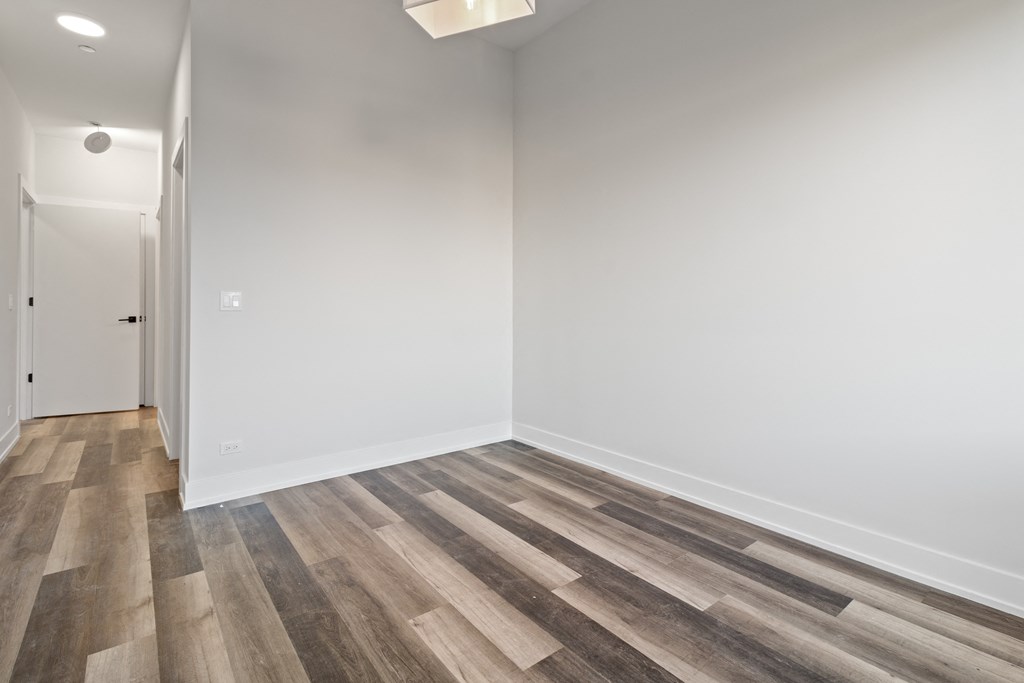 an empty room with wood flooring and white walls