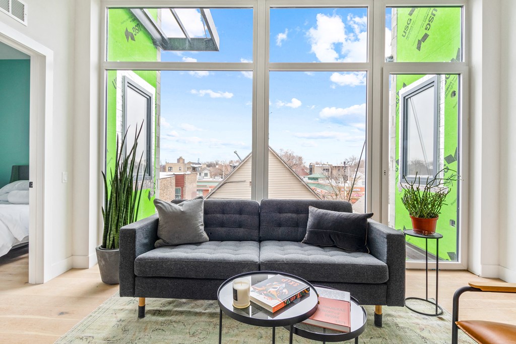 a living room with a couch and a table in front of large windows