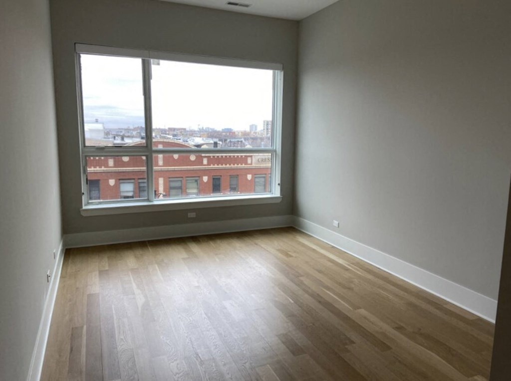 an empty living room with a large window and wooden floors
