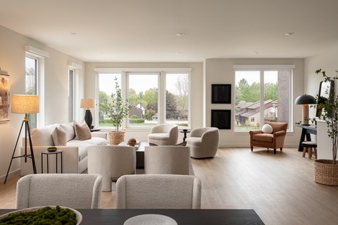 A modern living room with white furniture and a large window.