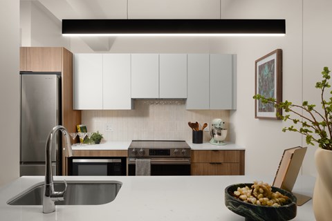 A modern kitchen with a stainless steel refrigerator and a bowl of fruit on the counter.