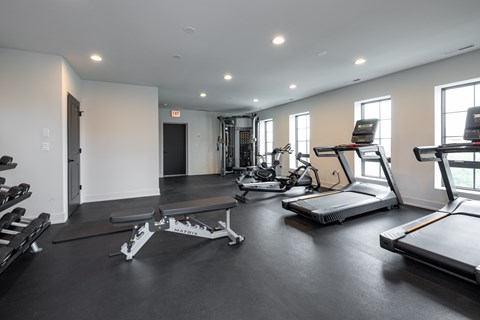 A spacious gym with treadmills, elliptical machines, and weight benches.