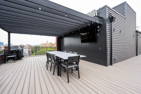 A black building with a white table and chairs in front.
