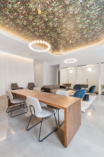 a long table with chairs and a couch in a room with white walls and a ceiling with