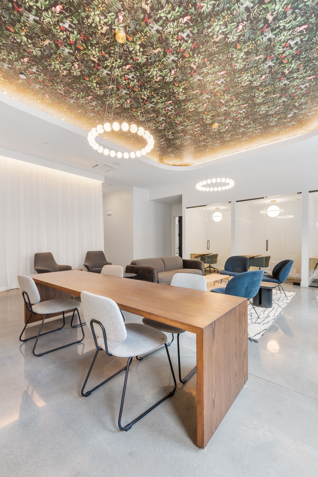 a long table with chairs and a couch in a room with white walls and a ceiling with