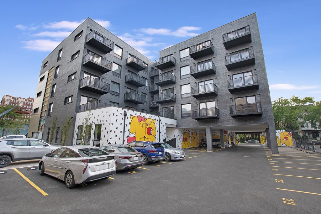 a large grey apartment building with a large parking lot in front of it