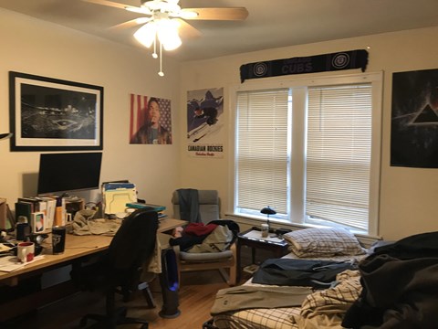 a bedroom with a desk and a bed and a window