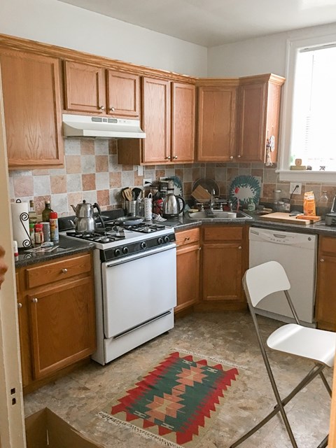 A kitchen with wooden cabinets and a white stove top oven.