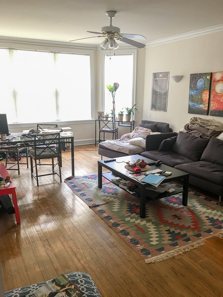 A living room with a brown couch and a rug.