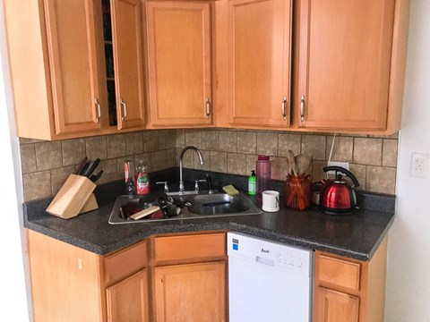 A kitchen with wooden cabinets and a white dishwasher.