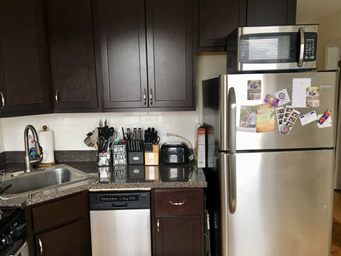 A kitchen with a stainless steel refrigerator and a microwave above it.