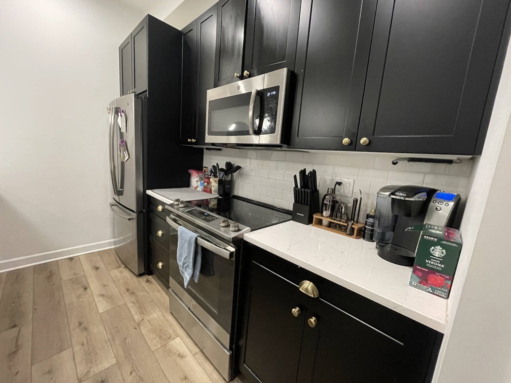 a kitchen with black cabinets and stainless steel appliances and a white counter top