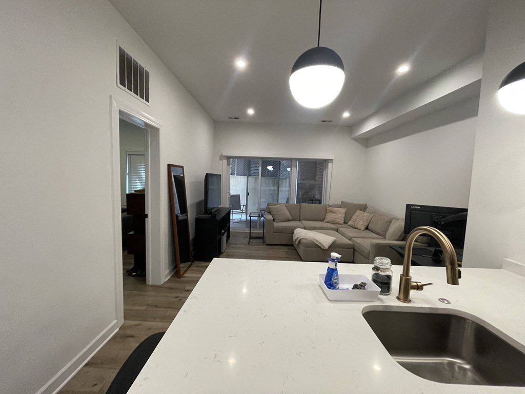 a kitchen and living room with a white counter top and a sink