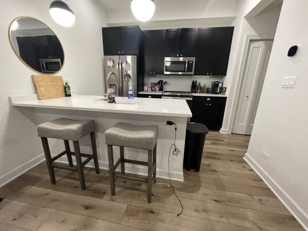 a kitchen with black cabinets and a counter top with two stools