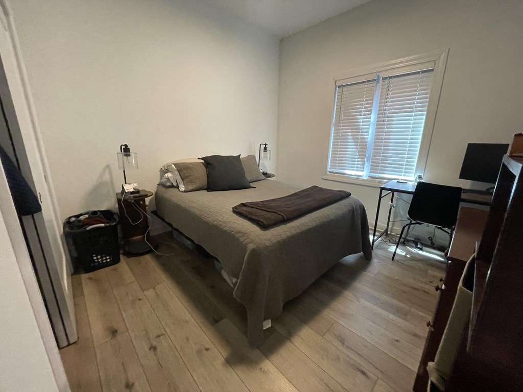 a bedroom with a bed and a desk and a window