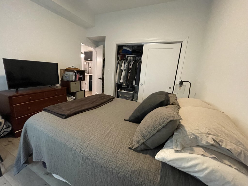 a bedroom with a bed and a dresser and a tv