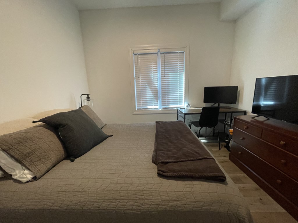 a bedroom with a bed and a desk with a tv