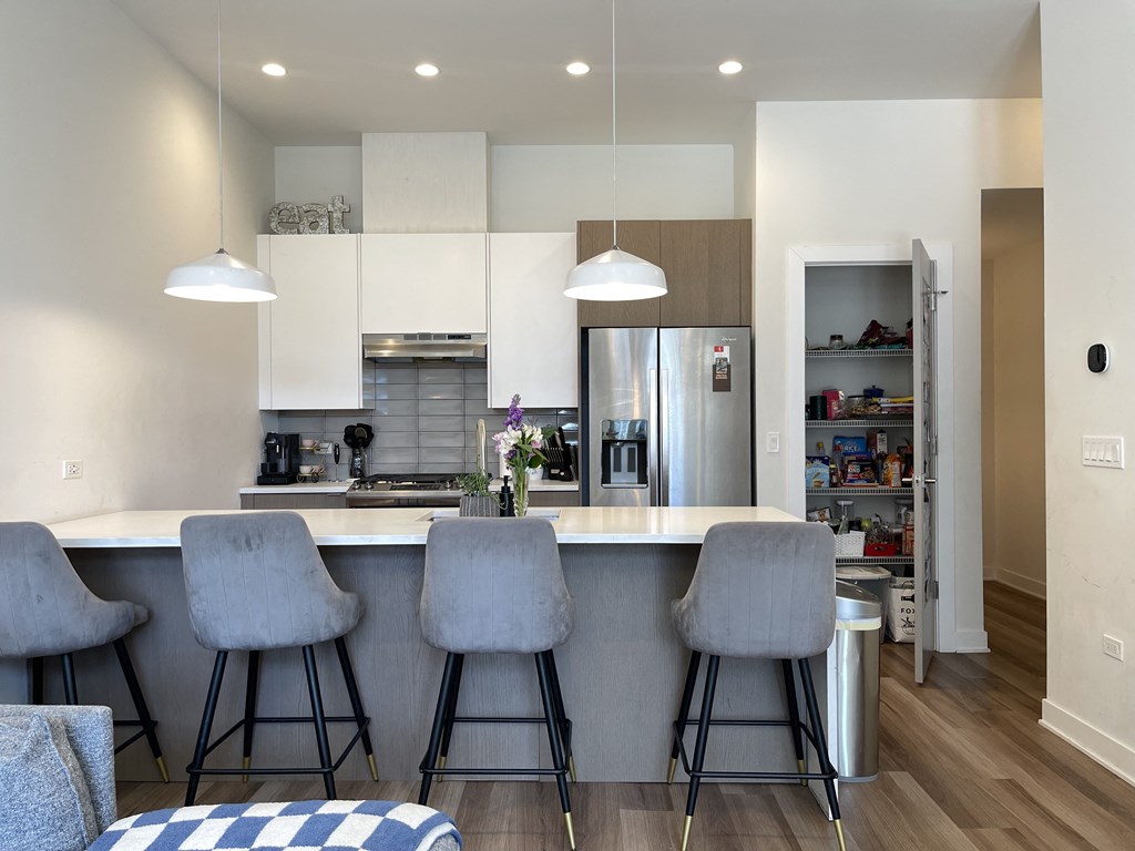 a kitchen with white cabinets and a large island with three stools