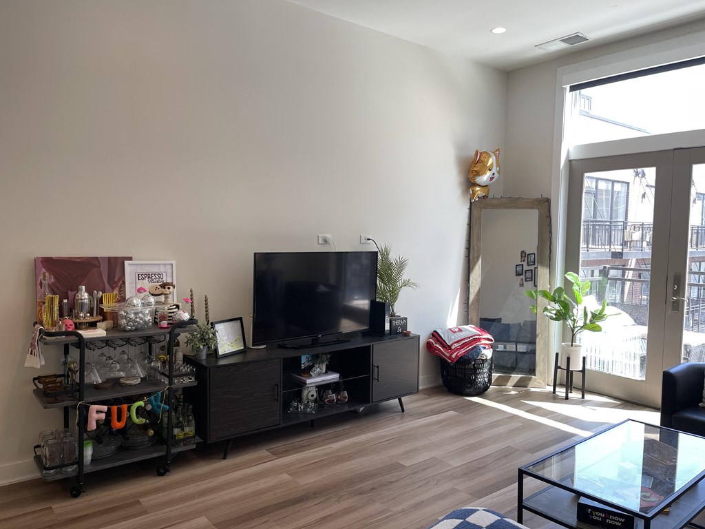 a living room with a tv and a door to a balcony