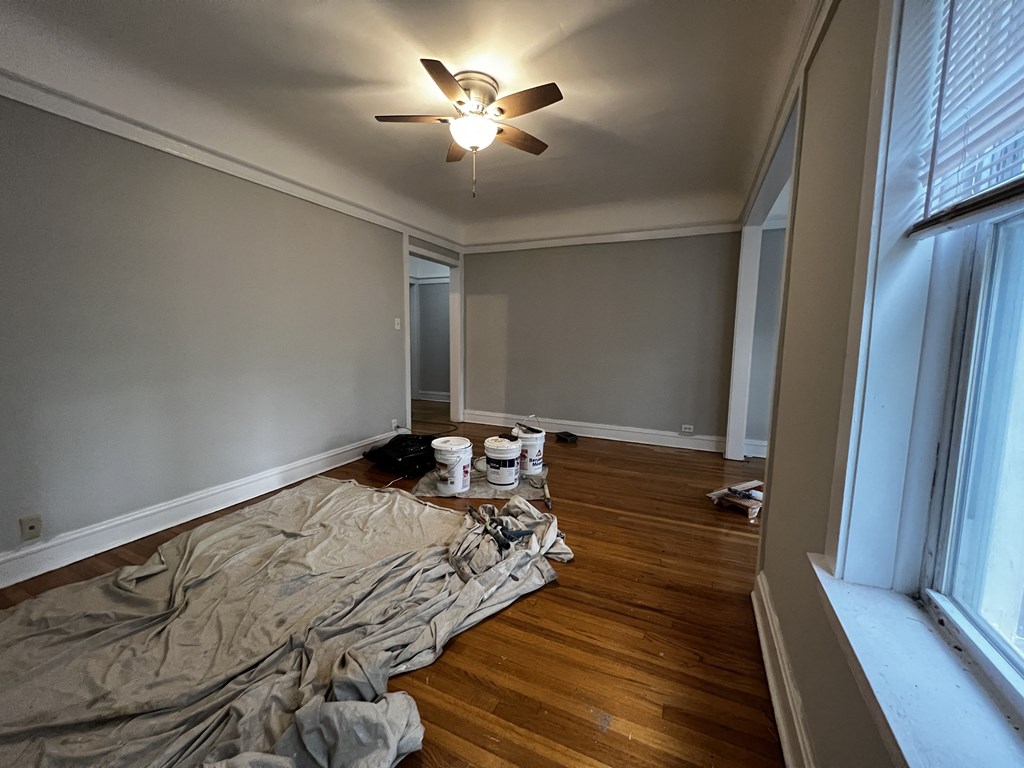 a living room with a ceiling fan and blankets on the floor