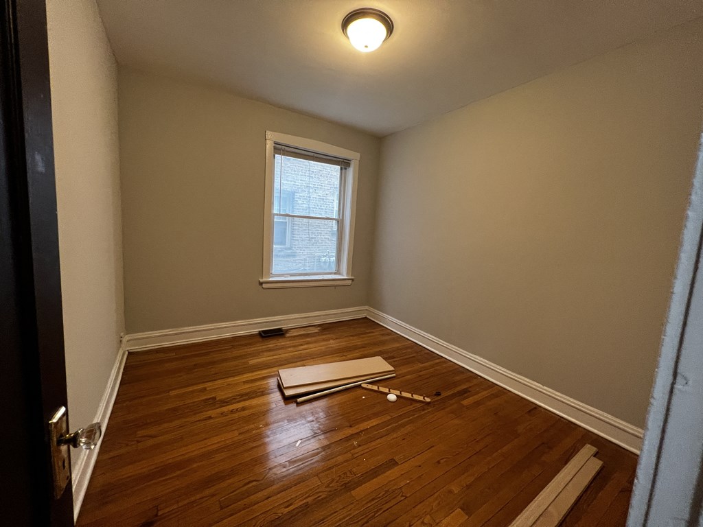 a bedroom with hardwood floors and a window