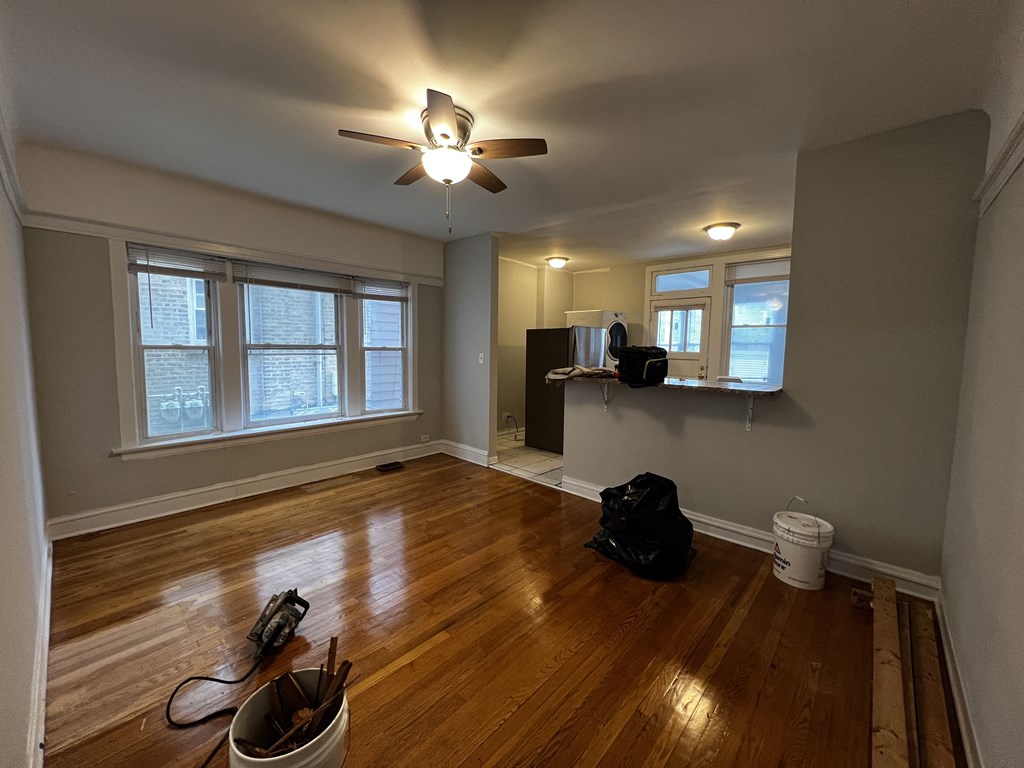 an empty living room with hardwood floors and a ceiling fan