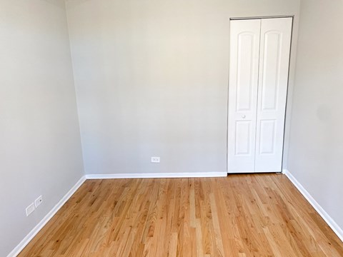 A room with a white door and wooden flooring.