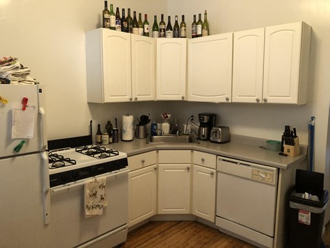 a small kitchen with white cabinets and a stove and refrigerator