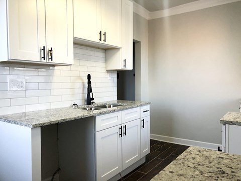 A kitchen with granite countertops and white cabinets.