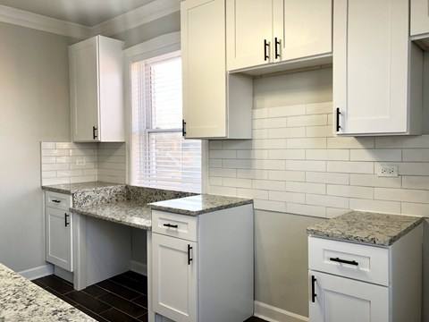 A kitchen with white cabinets and granite countertops.